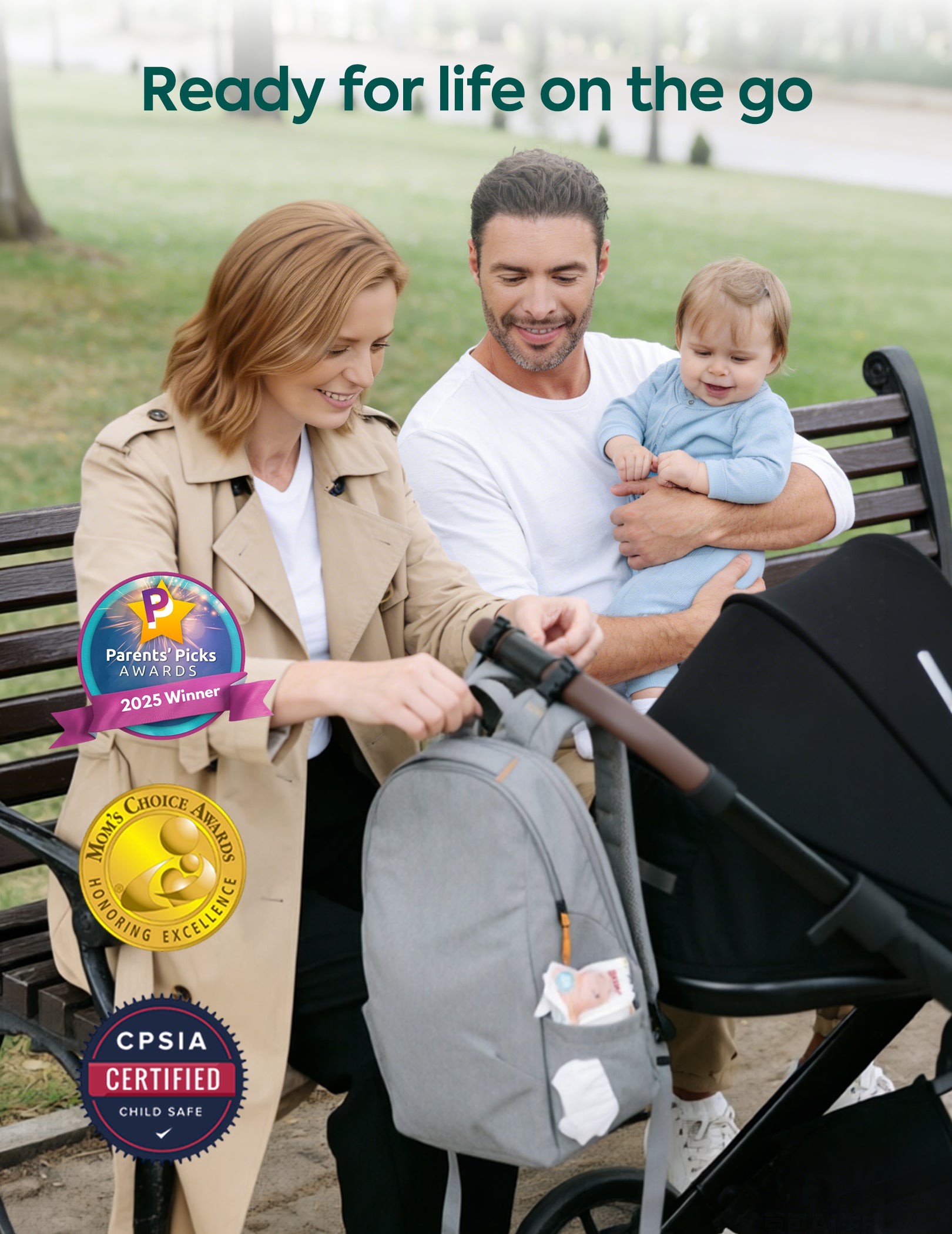 Woman holding a stroller with a baby, man holding a child, and a park bench in the background.#Color_Grey