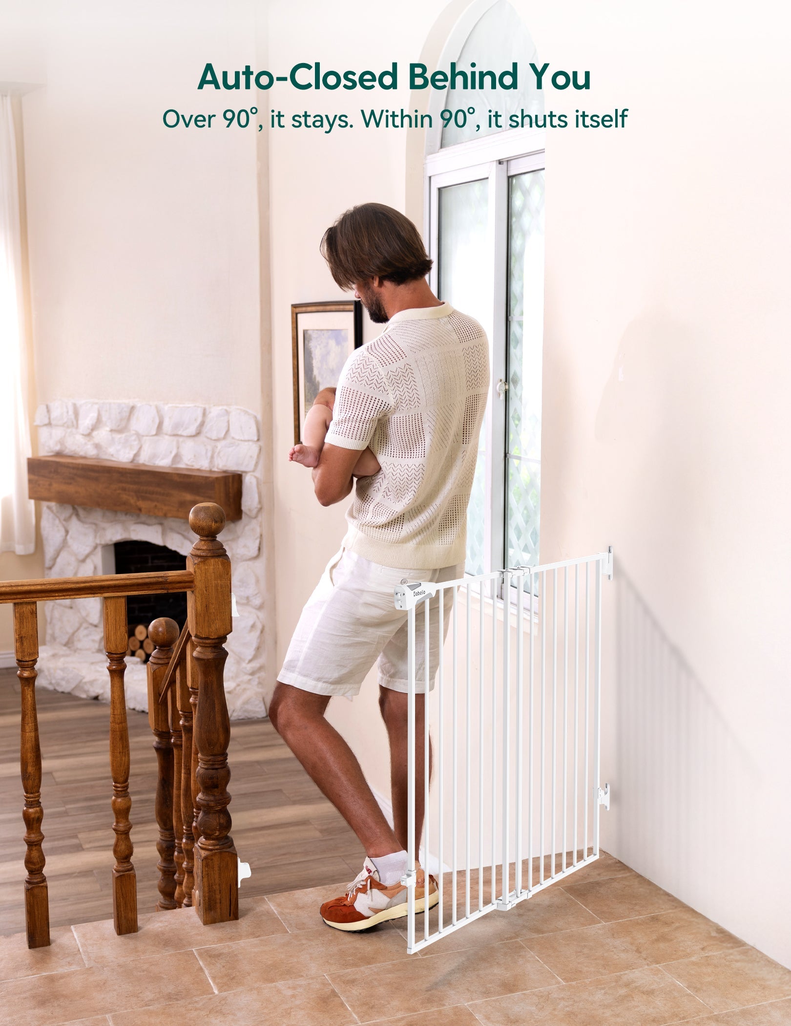Babelio baby safety gate installed on stairs in a living room, dad holding baby nearby
