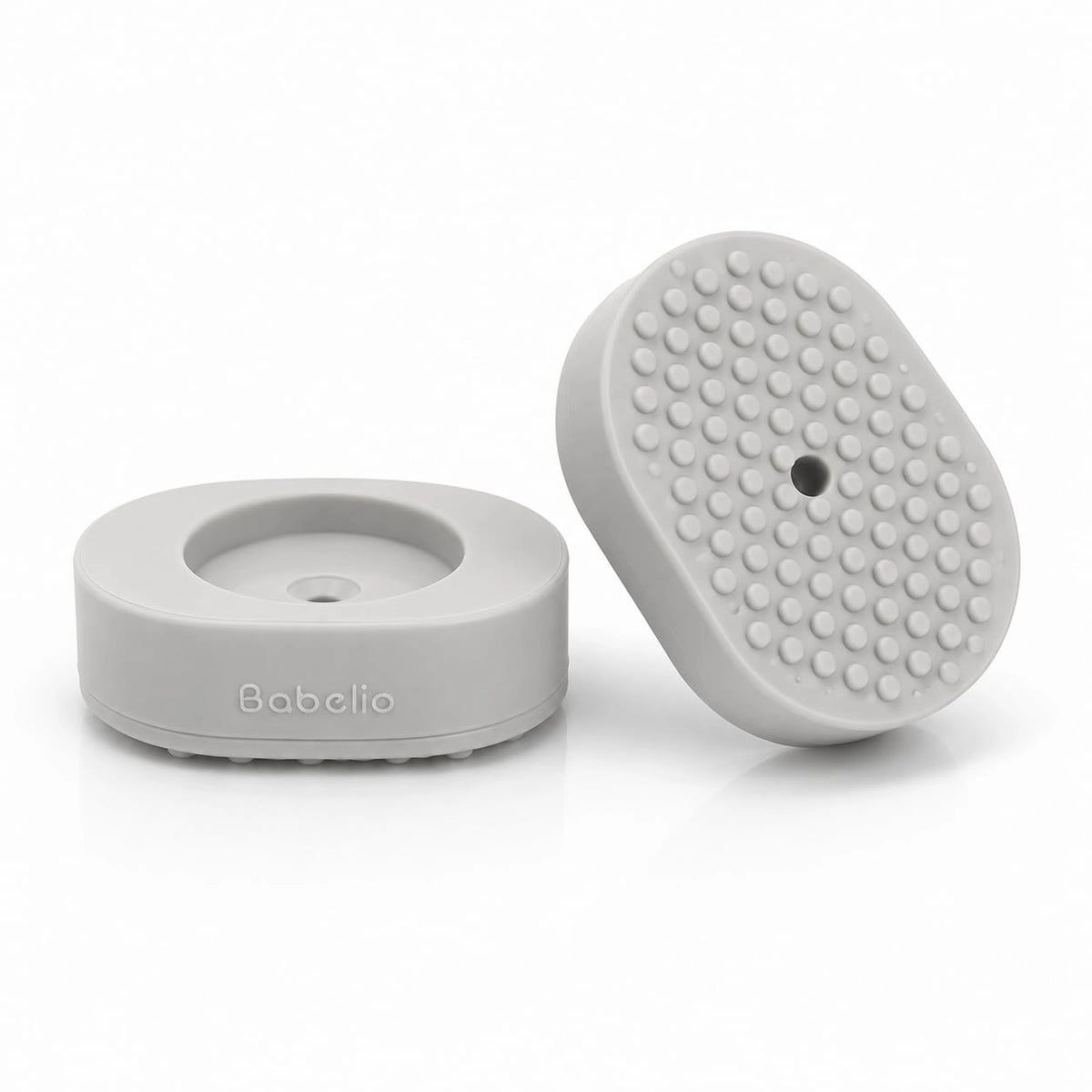 A light gray silicone baby massage or sensory pad shown from two angles on a clean white background. One view shows the circular base with the debossed brand name 'Babelio', and the other shows the textured, raised-dot top surface.#Color_White