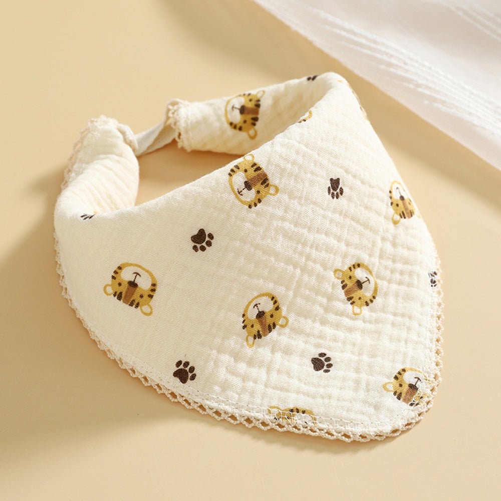 Babelio baby muslin bib with tiger and paw print design on a beige surface