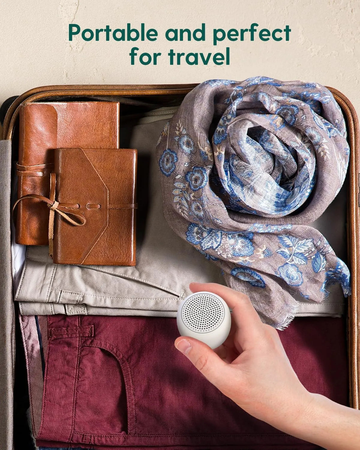 Babelio white noise machine held over packed suitcase, portable for travel