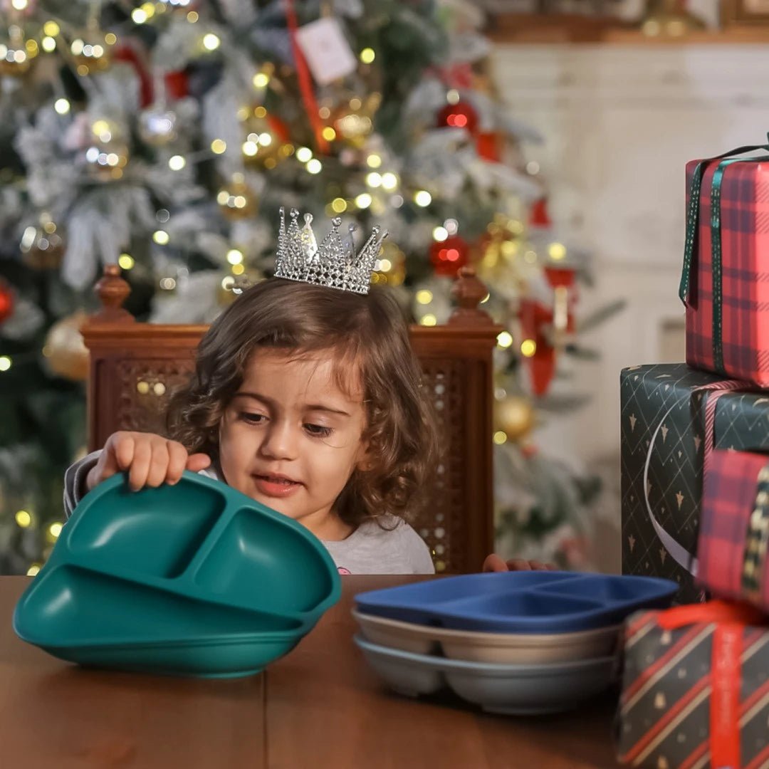 Toddler with Babelio baby suction plates set at festive dining table, holiday decor in background